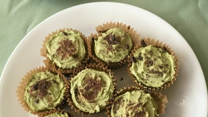 A plate of Matcha Chocolate Chip Cupcakes with a cup of green tea and a teapot