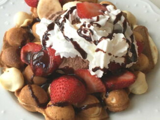 Bubble Egg Waffle Sundae piled high with ice cream, sliced strawberries, whipped cream, and chococlate sauce drizzle. #nutfree #dessert