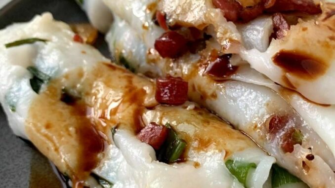 How-to-Make-Enough-Cheung-Fun-Rice-Noodle-Roll-Recipe close up of rice noodle rolls with a drizzle of sweet soy sauce on a grey plate