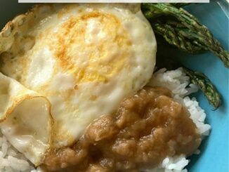 Dairy-free beef gravy over rice, served with an over easy egg and roasted asparagus in a blue bowl
